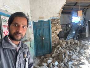 Lok Mani in front of a collapsed Birthing Center