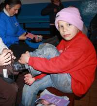 Boy being fit for boots by CERI volunteer