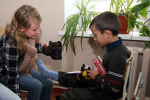 Volunteer student puts boots on orphan's feet