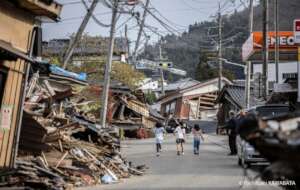 Children play next to a collapsed house
