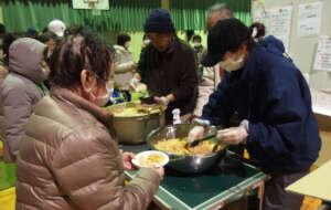 Victims line up for a soup kitchen in Suzu city