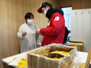 A woman receives honey in a tube from AAR staff