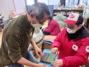 A man receives yokan on a tray from an AAR staff