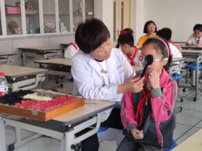 The doctor helping the kids with eye checkup