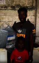 Claude Joseph and one of his children get tarps