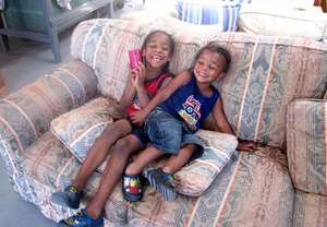 Cute sibs giggle on a sofa after picking new cups!