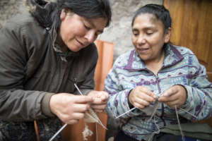 Silvia asks Rosa for guidance while knitting.