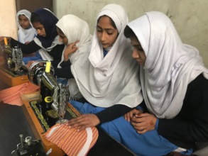 Girls stitching a shirt in the new sewing room