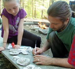 May studies the plaster cast tracks with Adam.