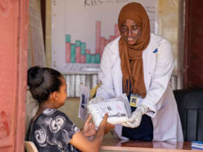 Midwife Zakia presents a delivery kit to Samher.