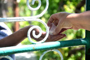 Angela Hands Maria TB Drugs Through Gate