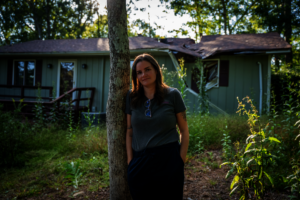 Hannah stands in front of her damaged home, in NC