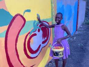Isabel painting a mural at Nunya Village
