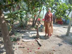 A woman stands helplessly by her dry hand pump.