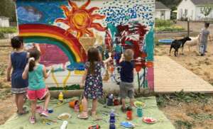 Kids facing cancer painting the goat house