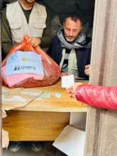 A woman presents a ticket to receive a winter kit.