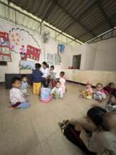 A teacher guides children to learn from books.