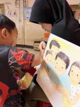 A teacher guides children to learn from books.