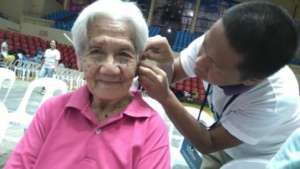 Nasim fitting a hearing aid to Christian woman