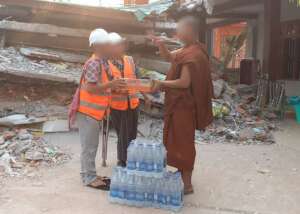 Partner staff members handing water to a monk