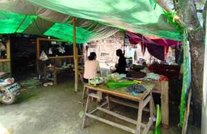 A simple tent set up in front of a damaged house