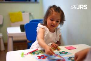 Girl smiles as she points to colorful flower shape