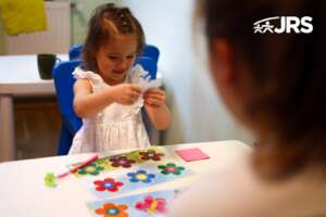 Girl holds flower during a speech therapy session.