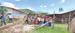 Children supported gather outside a rural school