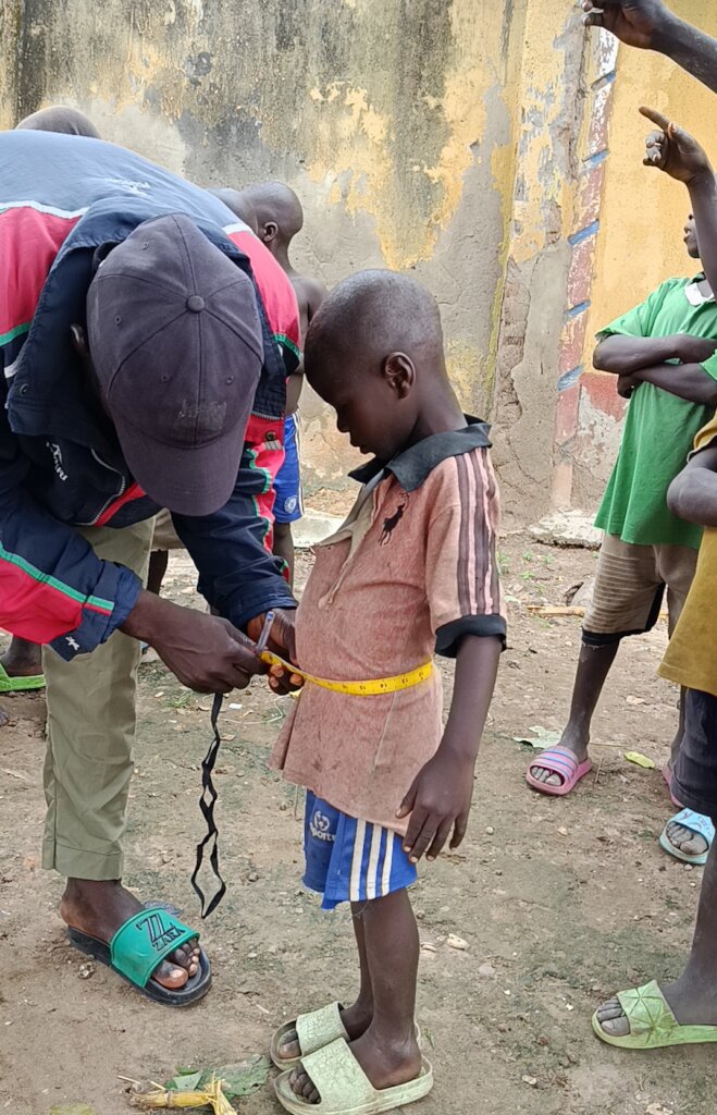 One of the children being measured by the tailor