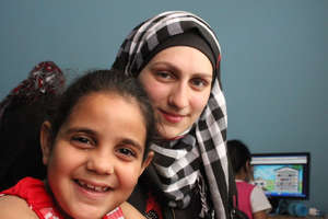 Volunteer Linda helps a child in the computer lab
