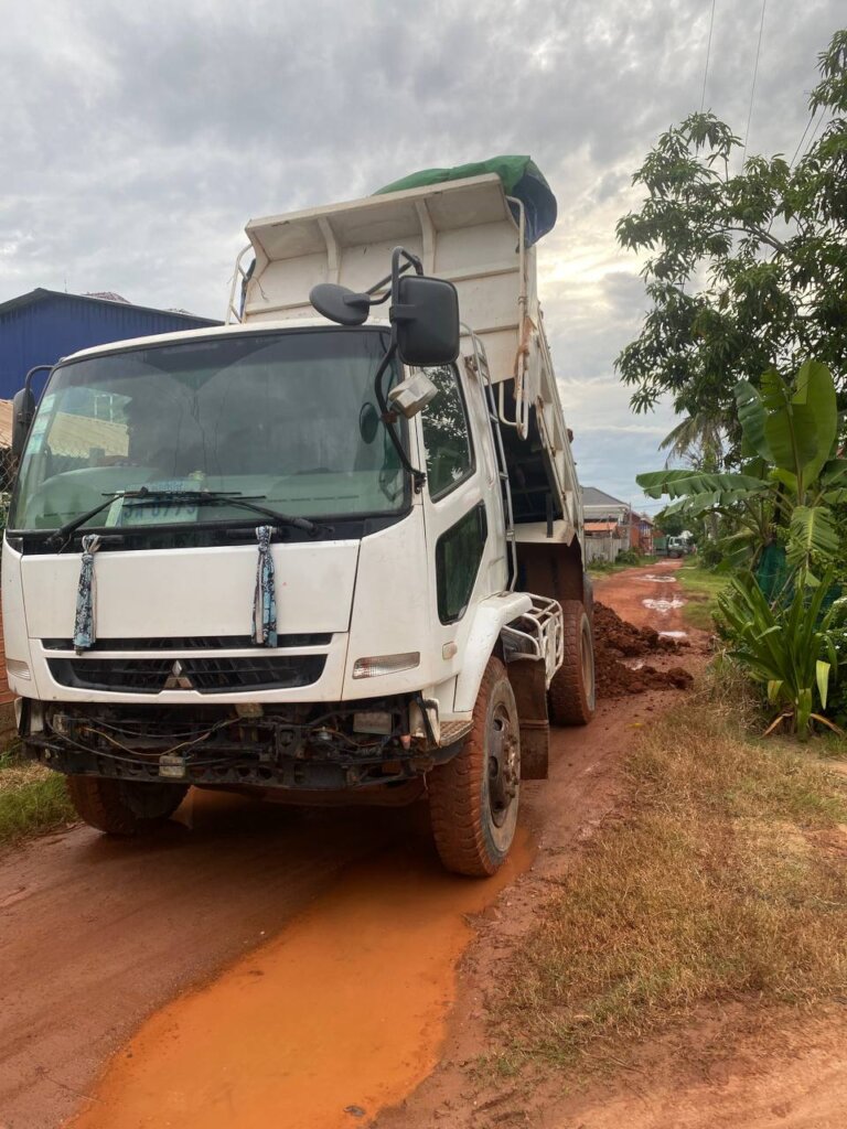 Truck bring red earth to broken roads