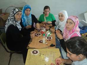 Women and youth create crafts at summer camp.