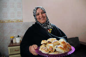 Ilham holds a tray of Mo'ajanat, a rolled pastry.