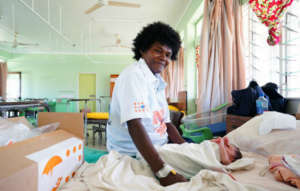 A mother sits with her baby in a health facility