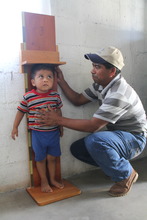Health promoter, Rogelio, measures a child