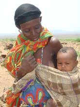 An Ethiopian woman walking with her baby and camel