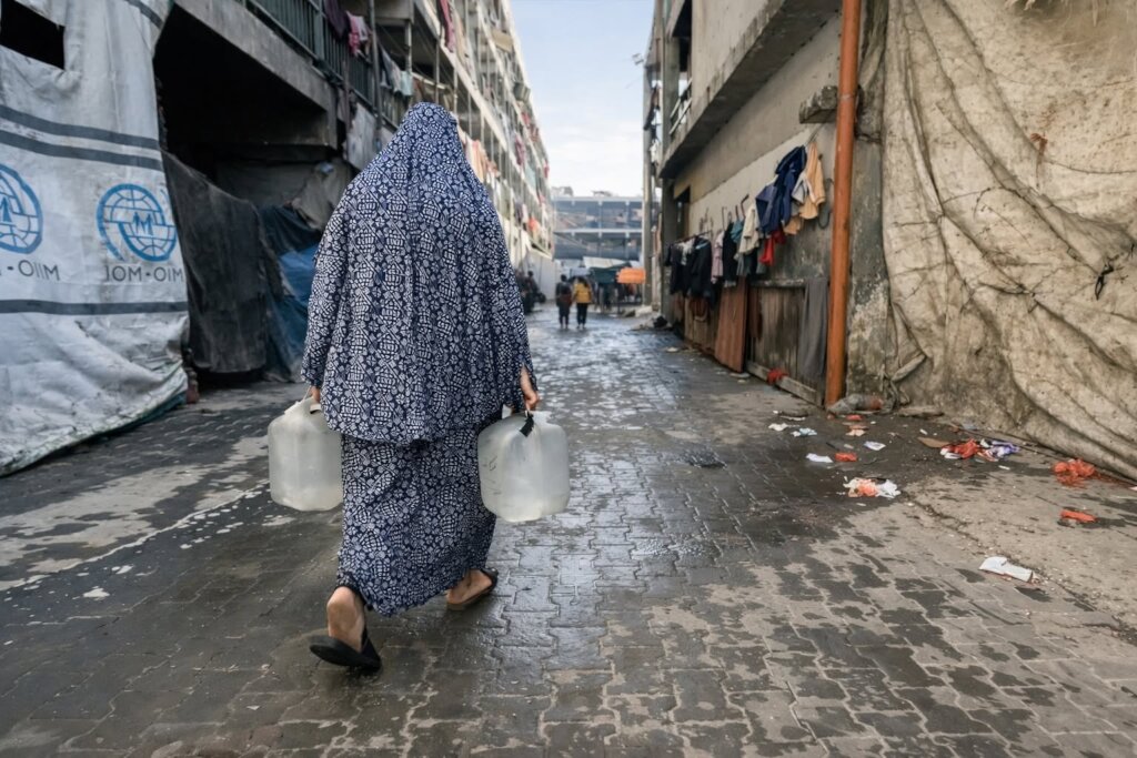 Woman carries water back from Peace Winds delivery