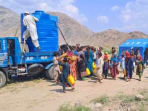 Disaster survivors gather at a water truck