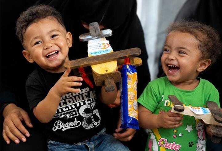 Children receive toys and treats at a tent camp