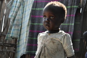 Adut* outside her home in South Sudan