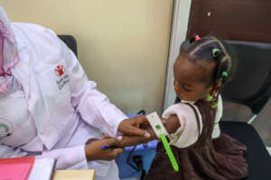 A health worker screens a child for malnutrition.