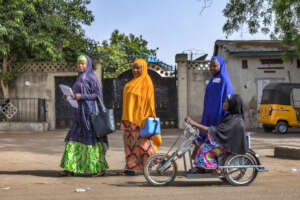 Vaccination team including Polio survivor on bike