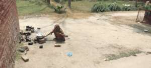 Flood-affected elderly woman cooking outside