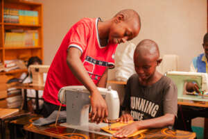 Alex and other children learning tailoring