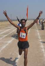 D.T. Dhebe raises his arms after winning the 10km