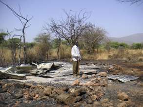 Lorititi standing at what is left of his house.