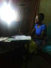 A school girl uses LED solar  lantern to study.
