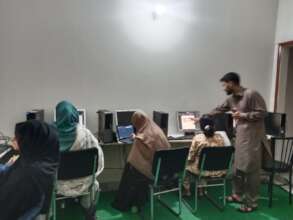 Female students at computers with instructor.