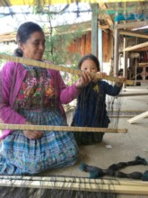 Vicenta teaches her granddaughter to weave.