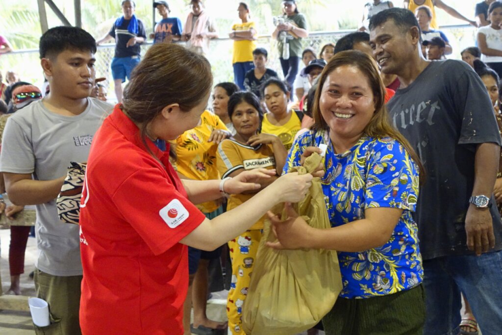A woman smiles after receiving relief supplies.